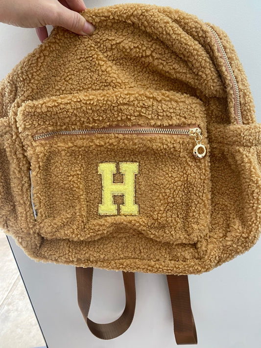 Brown backpack with initial 'H' in yellow **SAMPLE STOCK**