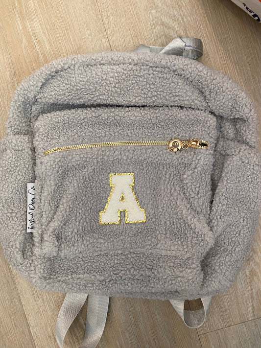 Grey backpack with initial 'A' in white ** SAMPLE STOCK**