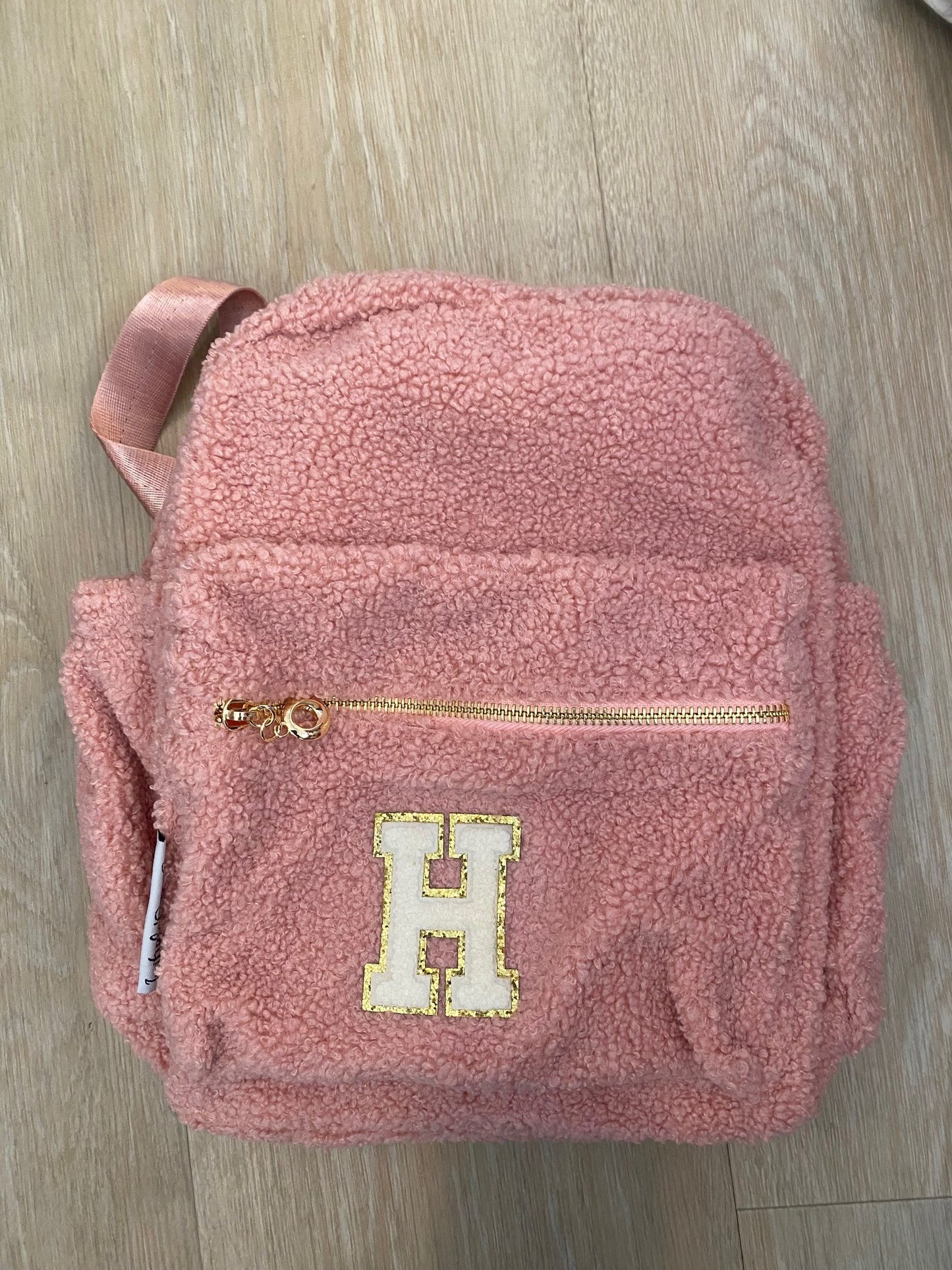 Pink backpack with initial 'H' in white **SAMPLE STOCK**