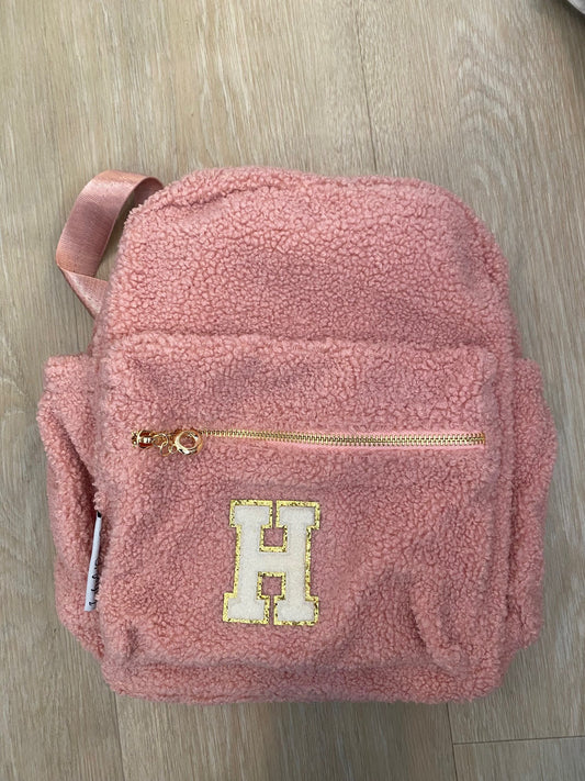 Pink backpack with initial 'H' in white **SAMPLE STOCK**