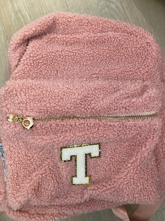 Pink backpack with initial 'T' **MATERIAL NEAR ZIP IS SLIGHTLY LIFTED**