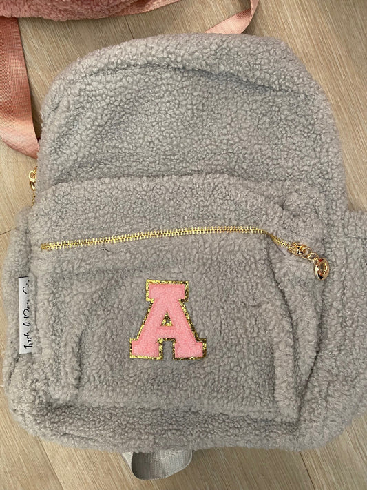 Grey backpack with initial 'A' in pink **SAMPLE STOCK**