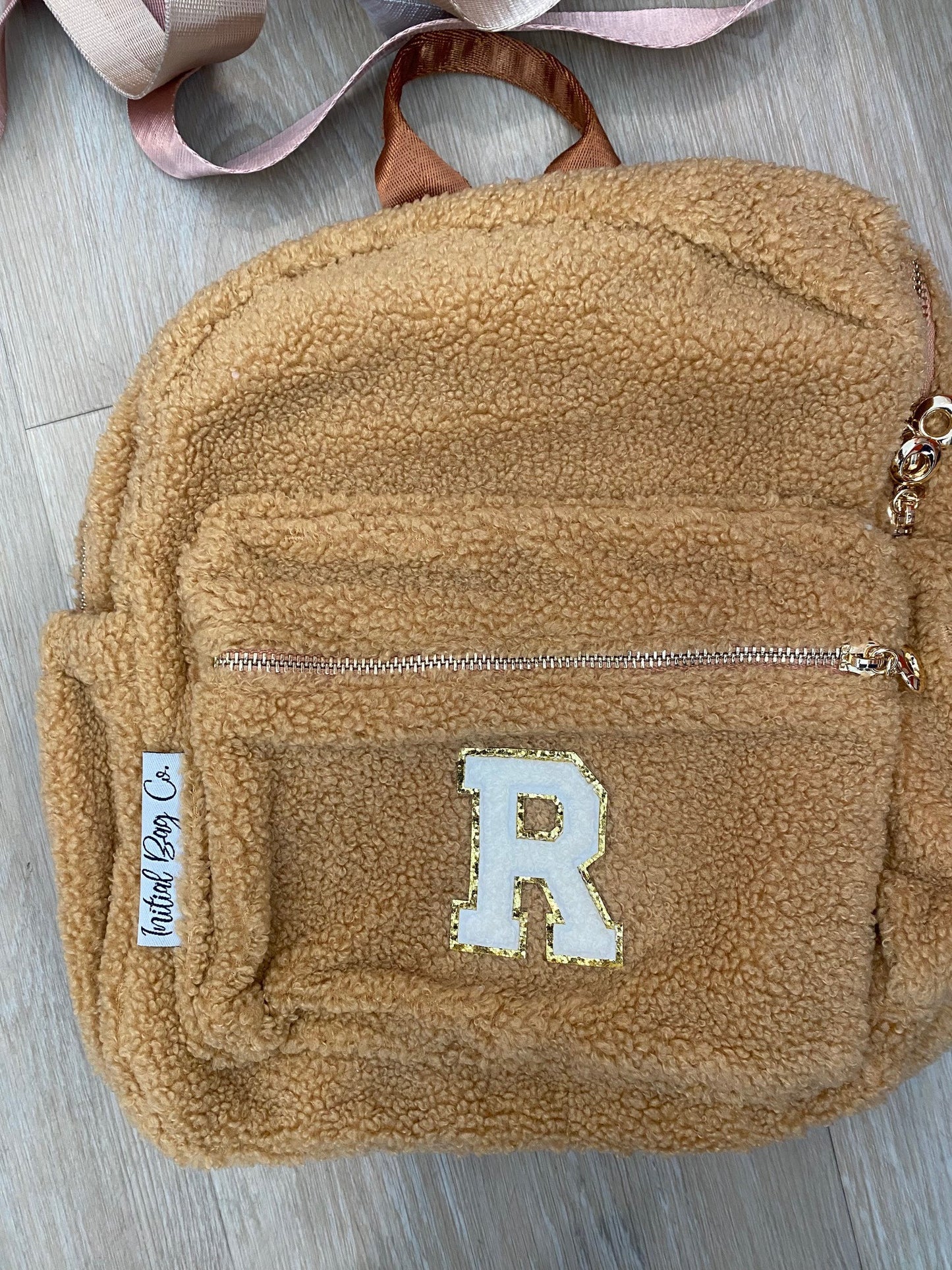 Brown backpack with initial 'R' in white **SAMPLE STOCK**