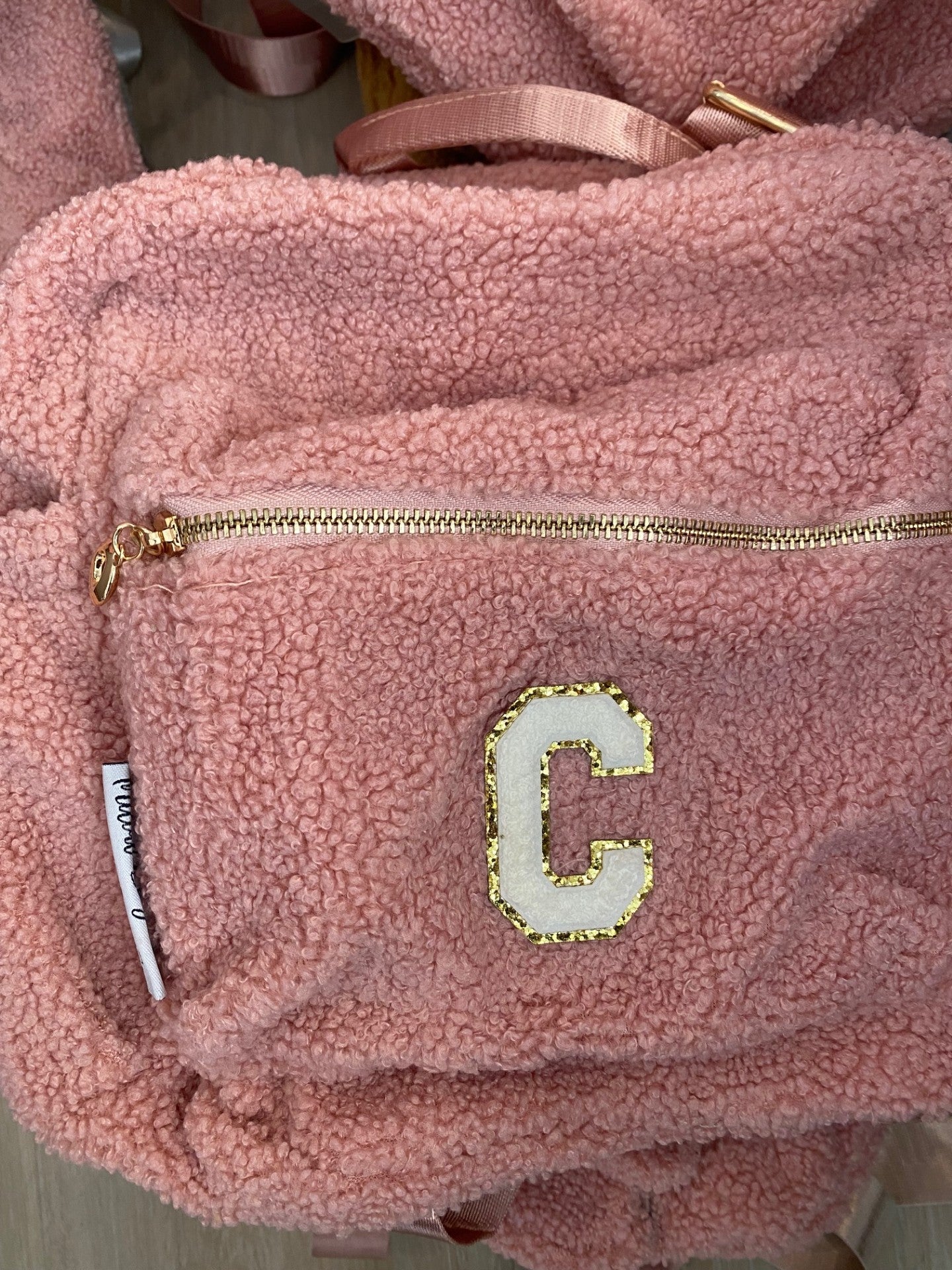 Pink backpack with initial 'C' in white **SAMPLE STOCK**